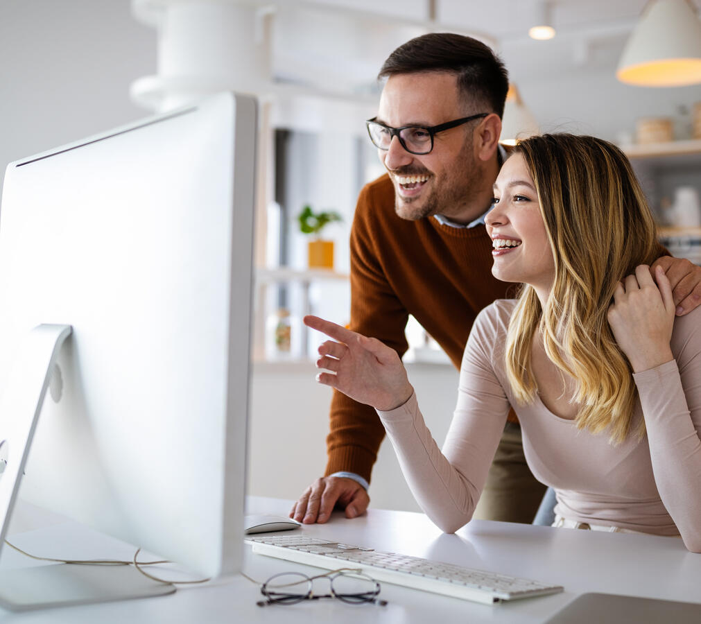 Young white couple looking at the screen of a computer together.