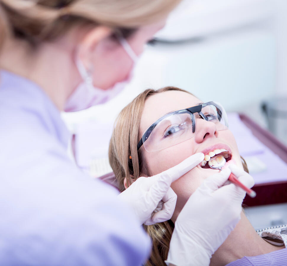 A dentist, examining the teeth of a young woman.