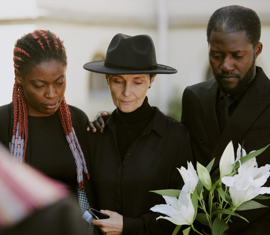 A multi-racial family dressed in black at a funeral.
