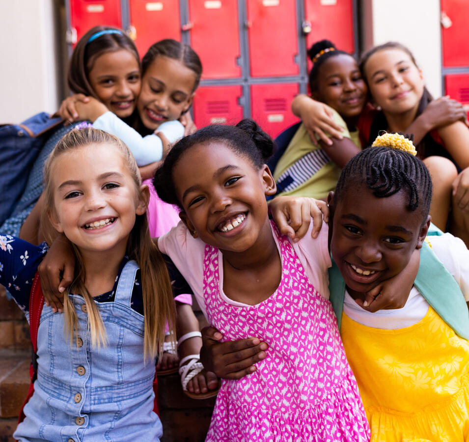 A group of 7 school children hugging and smiling.