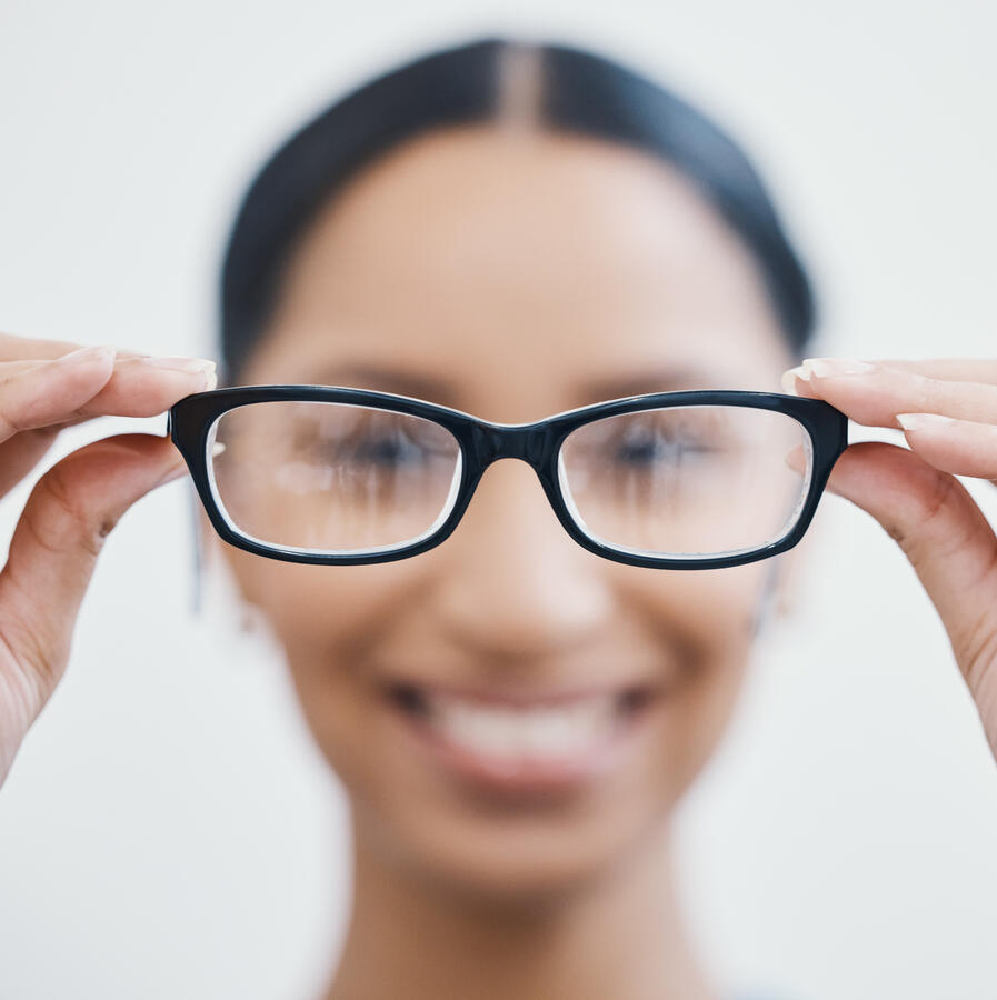 A young woman, putting on glasses.